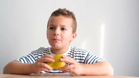 Little boy with appetite eats a pear. A healthy child eats fresh fruit. Stock Footage 213034057