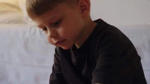 A little boy assembles a construction set while sitting on the floor. Stock Footage 252382379