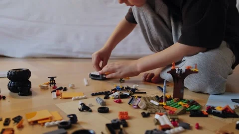 A little boy assembles a construction set while sitting on the floor. Stock Footage 252382411