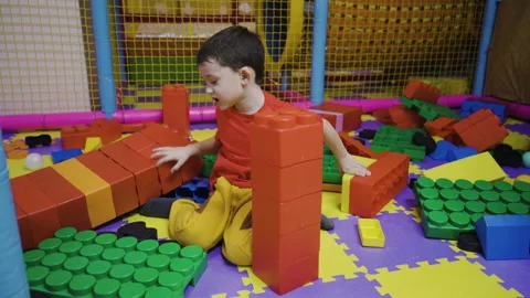 A little boy assembles a tower from a large construction set Stock Footage 169395911