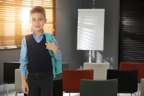 Little boy with backpack in empty school classroom Stock Photos