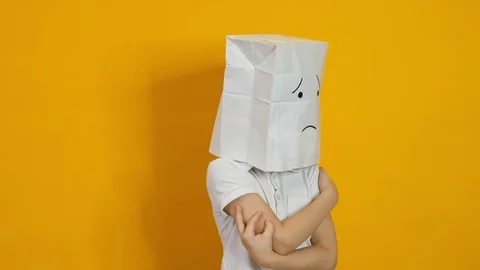 Little boy with a bag on his head - sad, dissapointed face on yellow background Stock Footage 123780931