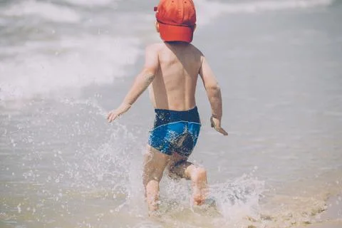 A little boy on the beach, playing with the waves Stock Photos