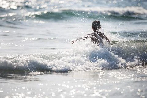 A little boy on the beach, playing with the waves Stock Photos