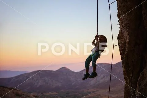 Little boy being lowered down while top rope climbing Stock Photos
