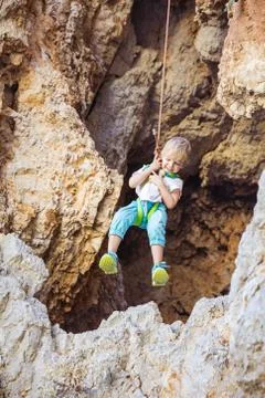 Little boy being lowered down while top rope climbing Stock Photos