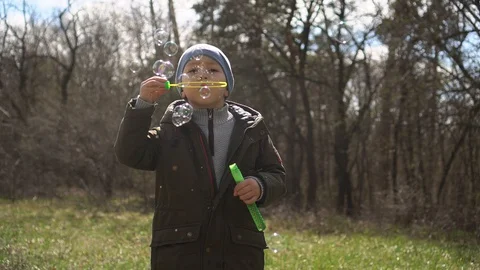Little boy blowing soap bubbles in the park.slow-mo Stock Footage 129090716