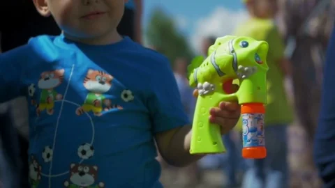 Little boy blows bubbles from a bubble gun Stock Footage 82405794