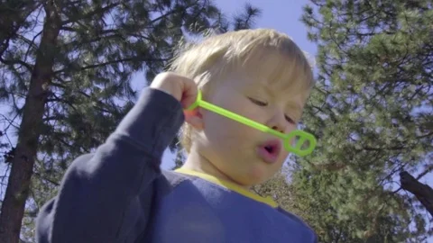Little boy blows bubbles using wand Stock Footage 74117805