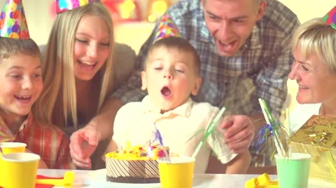 Little boy blows out candles on birthday cake at party Stock Footage 59082637