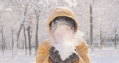 Little boy blows snow into the camera, joyful pink-cheeked child, sunny winter Stock-Footage 250154895