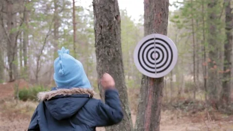 Little boy in blue jacket and funny cap throw cones at circle target Stock Footage 76560735
