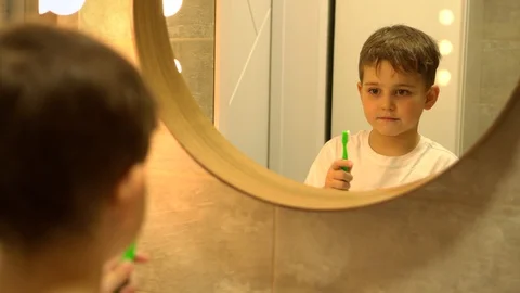 Little boy brushing his teeth in bathroom in front of mirror, oral hygiene Stock Footage 128778716
