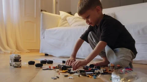 A little boy carefully assembles a construction set at home. Stock Footage 252382320