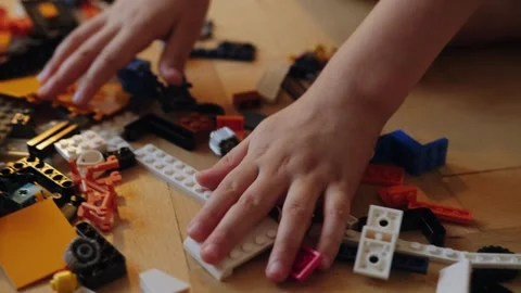 A little boy carefully assembles a construction set at home. Stock Footage 252382346