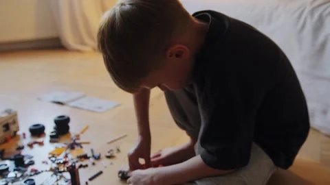 A little boy carefully assembles a construction set at home. Stock Footage 252382385