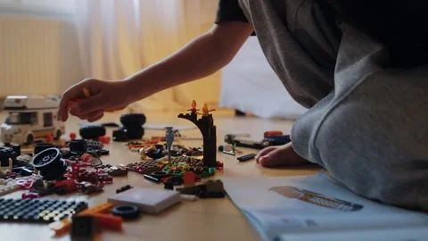 A little boy carefully assembles a construction set at home. Stock Footage 252382403