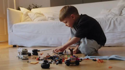 A little boy carefully assembles a construction set at home. Stock Footage 252382450