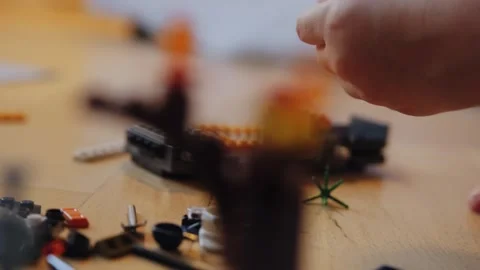 A little boy carefully assembles a construction set at home. Stock Footage 252382452