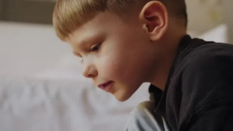 A little boy carefully assembles a construction set at home. Stock Footage 252382504