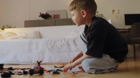 A little boy carefully assembles a construction set at home. Stock Footage 252382736