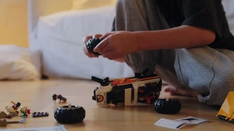 A little boy carefully assembles a construction set at home. Stock Footage 252382866