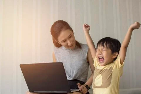 Little boy cheering while playing game in laptop Stock Photos