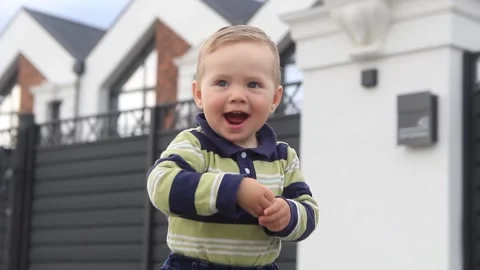 A little boy, a child, against the backdrop of a private house, shows something Stock Footage 201325762