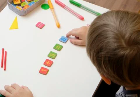 Little boy child preparing for elementary school doing simple math exercises. Stock Photos