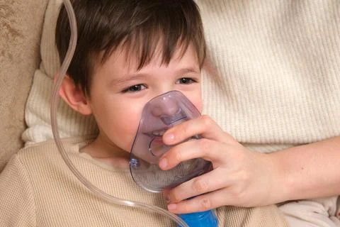 Little boy child using an inhaler mask for medical treatment. Nebulizer the.. Stock Photos