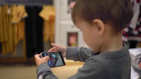 A little boy chooses clothes in the store and takes pictures of her on a Stock Footage 82078385
