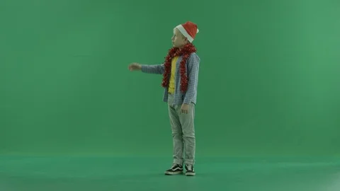 Little boy in Christmas hat points at something, green chroma key background Stock Footage 86204548