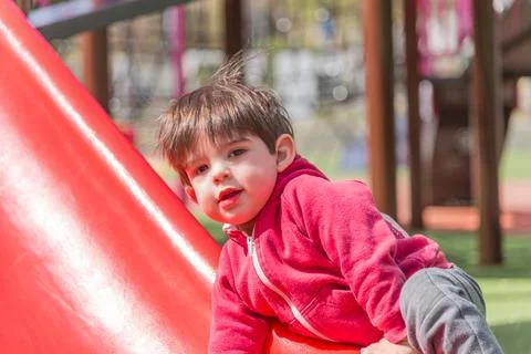 Little boy climbing the slide while having fun playing at the playground. Stock Photos