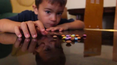 Little boy collect candy from the table and one eats them Stock Footage 65300779