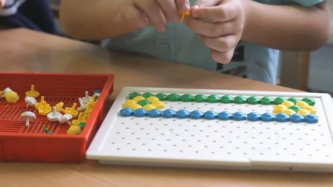 Little boy collecting pattern using colored chips Stock Footage 70970998