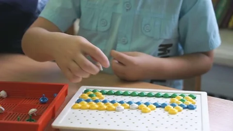 Little boy collecting pattern using colored chips Stock Footage 70971392