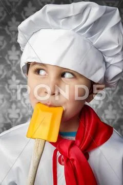 A little boy cook in uniform over vintage background playing with spoon Stock Photos