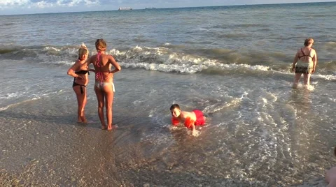 Little Boy Crawling on Pebble Beach in Sea Waves in Hot Sunny Day Stock Footage 65257593