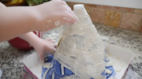 Little boy creating volcano out of paper mache for a science project Stock Footage 86292490