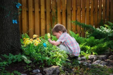 Little boy crouching down looking for easter eggs Stock Photos
