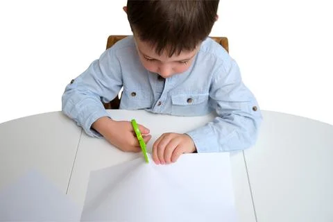 Little boy cutting white paper with safety scissors at table isolated on whit Stock Photos