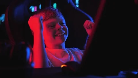 A little boy in a dark computer club with lots of computers is playing a game. Stock Footage 330869503