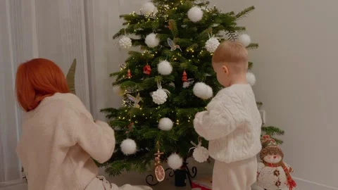 Little boy decorates Christmas tree with mother at home Stock Footage 346697975