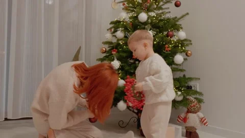Little boy decorates Christmas tree with mother in cozy home setting Stock Footage 346698355