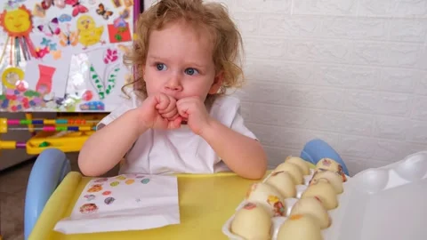 Little boy decorating easter eggs with stickers at a table. Child engrossed in Stock Footage 330108839