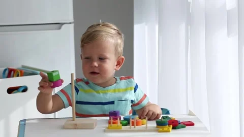 A little boy disassembles and assembles a wooden pyramid. Stock Footage 142223203
