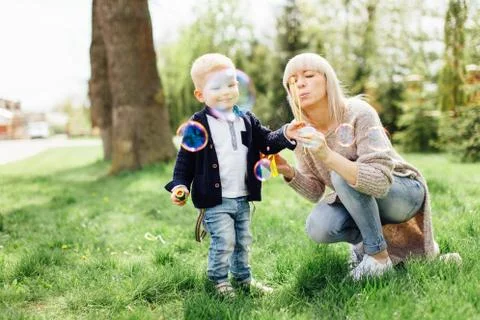 Little boy do bubbles with his mother at park Stock Photos