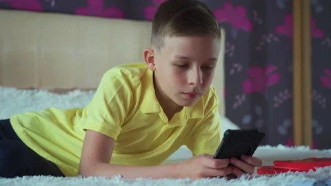 Little boy does homework, reads a book in bed. Books are scattered on the bed, Video stock 132035418