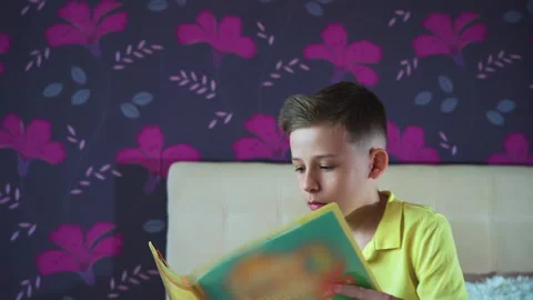 Little boy does homework, reads a book in bed. Books are scattered on the bed, Stock Footage 132035516
