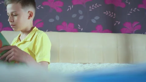 Little boy does homework, reads a book in bed. Books are scattered on the bed, Video stock 132035889